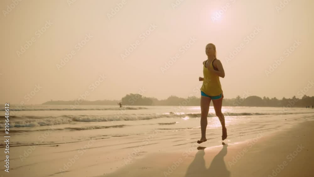 Running woman. Runner girl trains and jogging on the beach in sunny day light in the sea background. Female fitness training outdoors on summer day, 4K Running woman. Runner girl trains and jogging on the beach in sunny day light in the sea background. Female fitness training outdoors on summer day, 4K