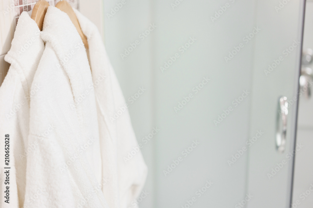 Clean white towel and bathrobe on a hanger prepared to use. Bathroom Inside rooms of a apartment or hotel.