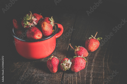 Strawberries in an iron mug on a wooden table. photo