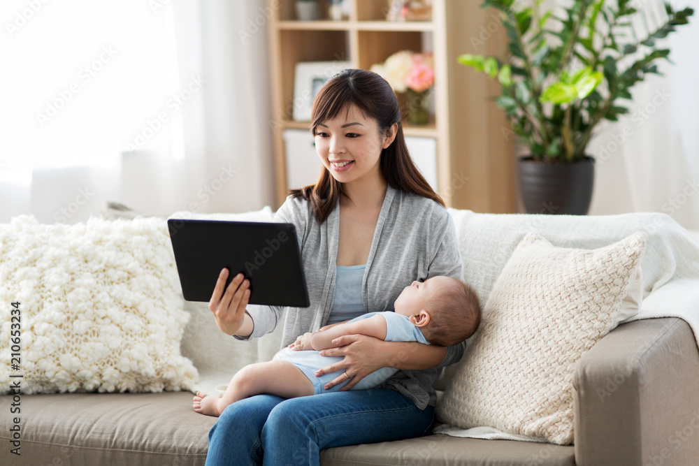 family, technology and motherhood concept - happy smiling young asian mother with sleeping baby and tablet pc computer at home family, technology and motherhood concept - happy smiling young asian mother with sleeping baby and tablet pc computer at home