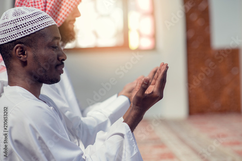 Two religious muslim man praying together inside the mosque