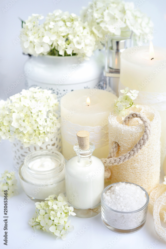 Spa composition with candles, cream, salt and flowers of hydrangea on a white background