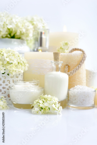Spa composition with candles, cream, salt and flowers of hydrangea on a white background