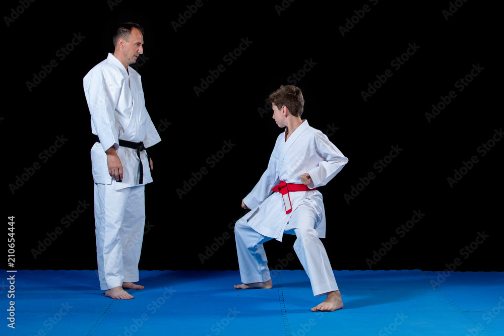 Male karate instructor training little children in dojo