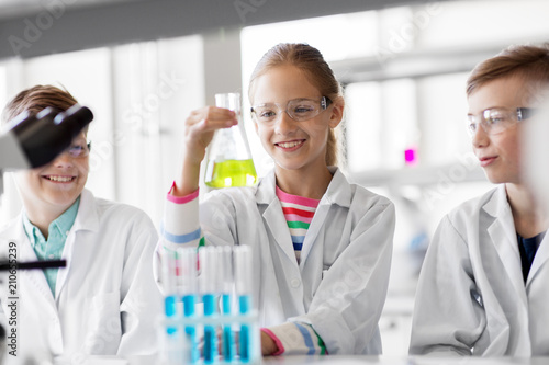 education, science and children concept - kids with test tubes studying chemistry at school laboratory photo