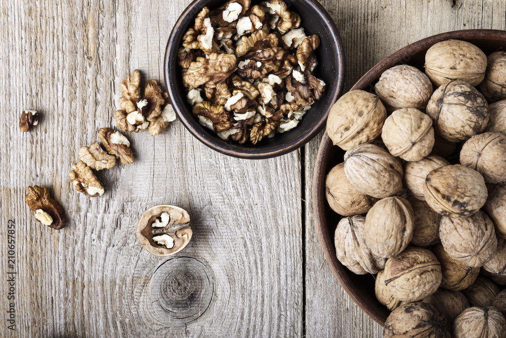 Walnut kernels in a bowl and whole walnuts on table. Walnut kernels in a bowl and whole walnuts on table.