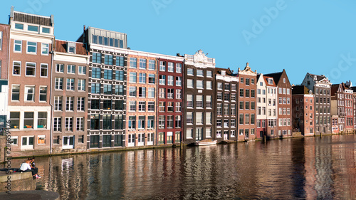 Sunset in Amsterdam city. Old duty buildings and reflections on canal. © juhrozian
