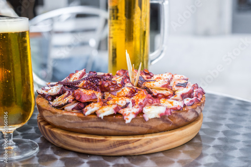 Fototapeta Naklejka Na Ścianę i Meble -  Glasses of cold Beer and Wooden plate of galician style cooked octopus with paprika and olive oil. Pulpo a la gallega