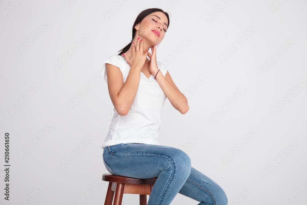 seductive woman in white t-shirt massaging her neck while sitting seductive woman in white t-shirt massaging her neck while sitting