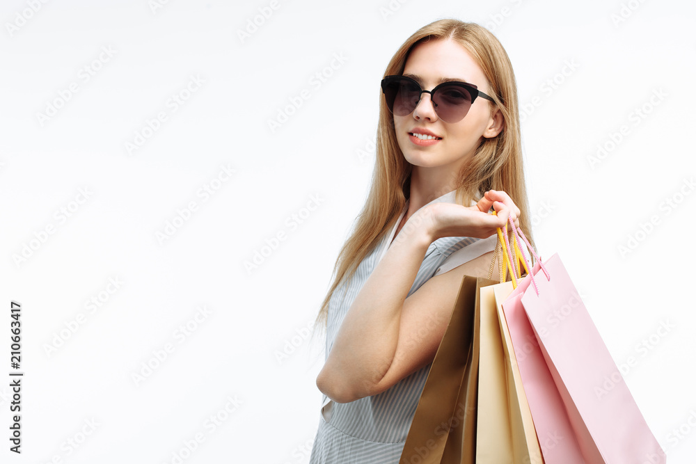 Young beautiful girl in glasses shopping, posing with gift bags, on white background, suitable for advertising, text insertion Young beautiful girl in glasses shopping, posing with gift bags, on white background, suitable for advertising, text insertion
