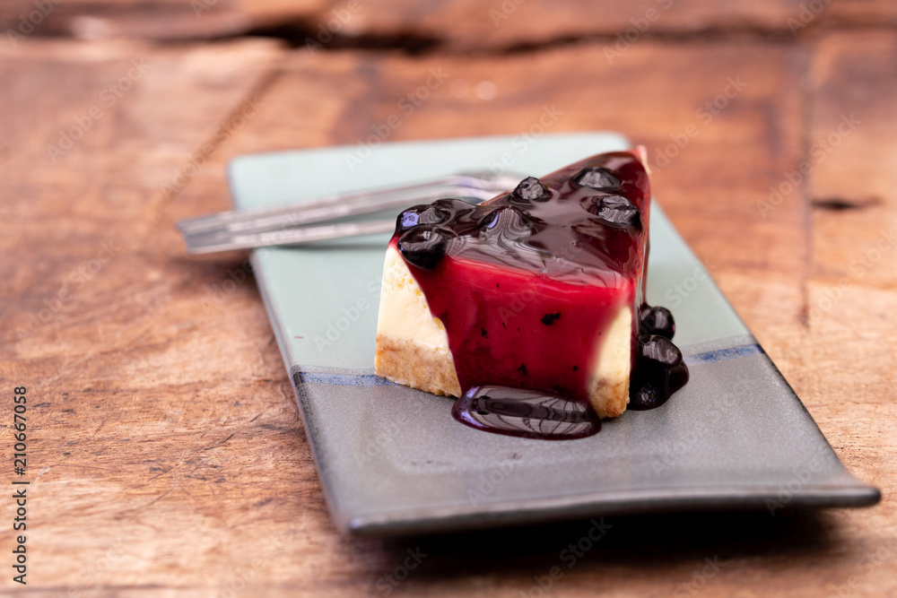Tasty and delicious cheesecake dessert with berry fruit made on top served plate on wooden table. Tasty and delicious cheesecake dessert with berry fruit made on top served plate on wooden table.