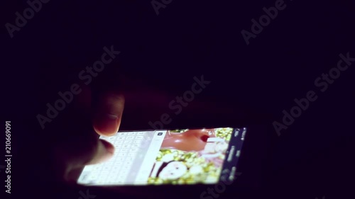 Close up of man hands typing scrolling pictures phone at night.