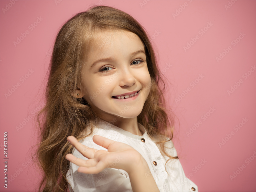 The happy teen girl standing and smiling against pink background. The happy teen girl standing and smiling against pink background.