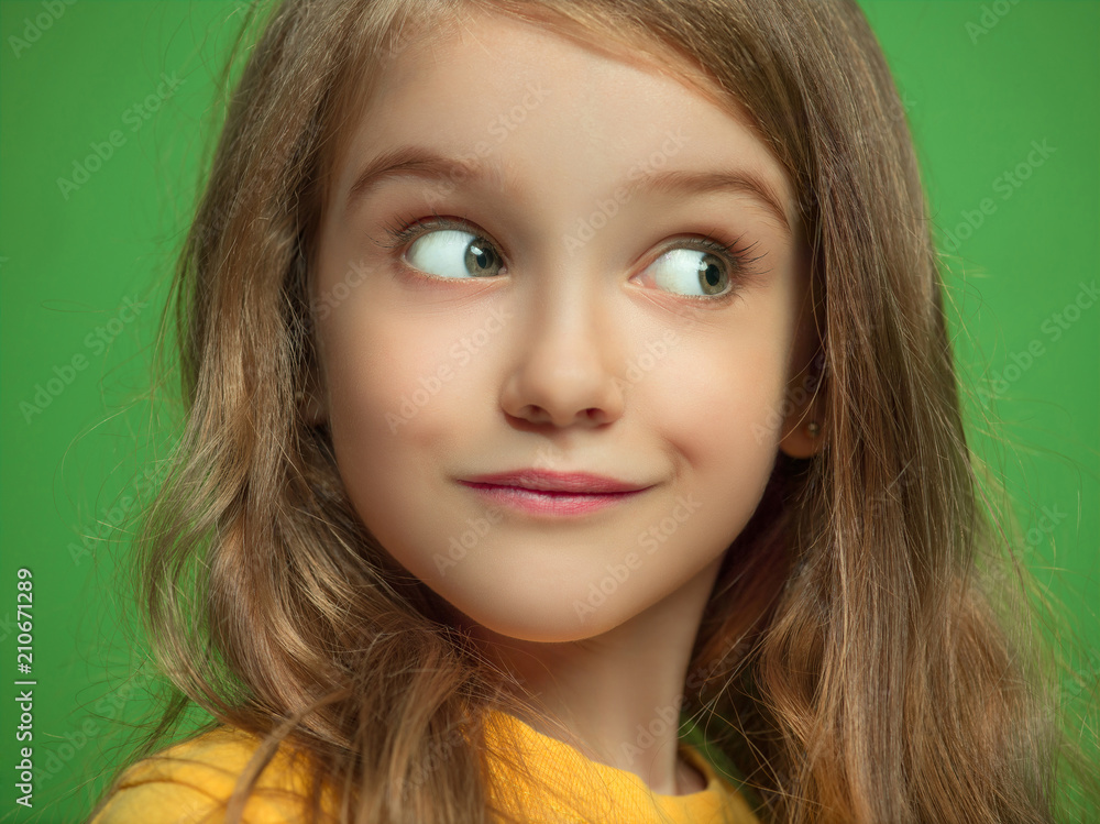 The happy teen girl standing and smiling against green background. The happy teen girl standing and smiling against green background.