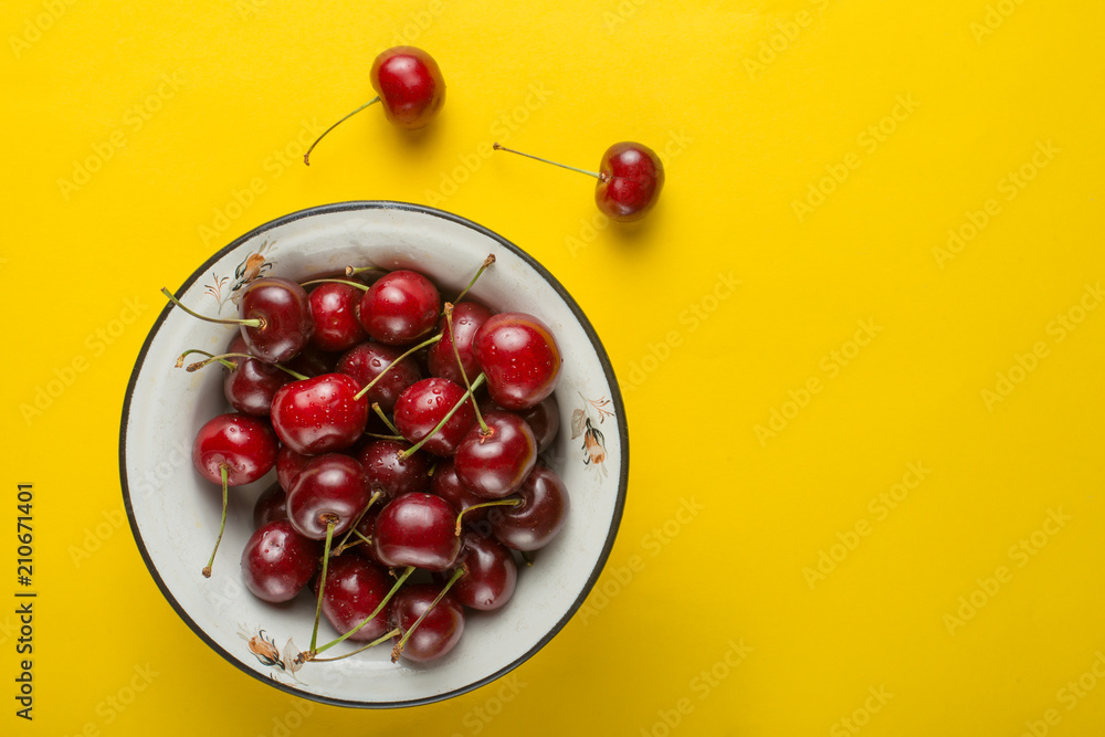 Sweet cherries in a bowl, on a yellow background Sweet cherries in a bowl, on a yellow background