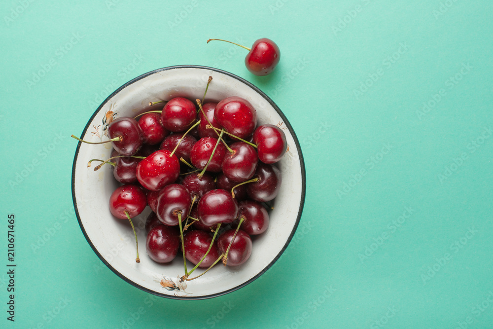 Sweet cherries in a bowl, on a green background Sweet cherries in a bowl, on a green background