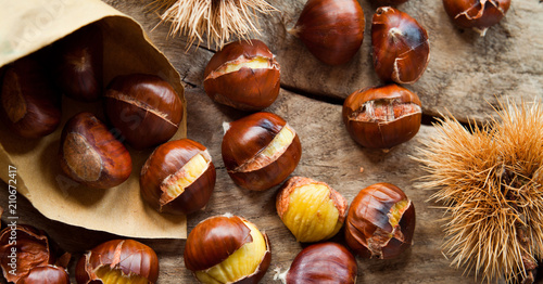 Roasted Sweet Chestnuts nuts on neutral wooden background closeup, macro, detail -  healthy seasonal snack.