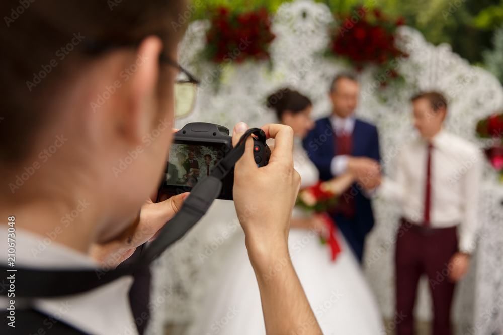 Photographer taking a photo of the happy marriage couple during the wedding ceremony. Selective focus. Photographer taking a photo of the happy marriage couple during the wedding ceremony. Selective focus.