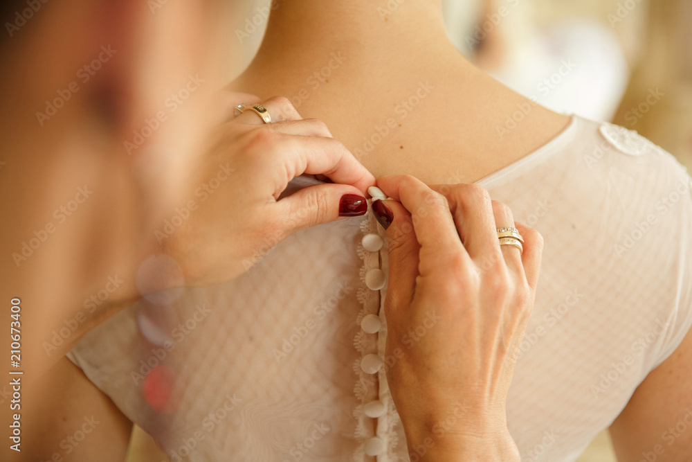Bridesmaid helps a bride to wear a wedding dress. Wedding concept. Close-up view.