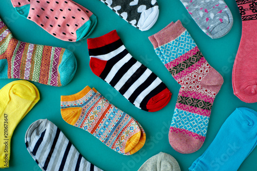 Many socks are scattered on a turquoise background. Knitted socks for cold seasons. View from above.