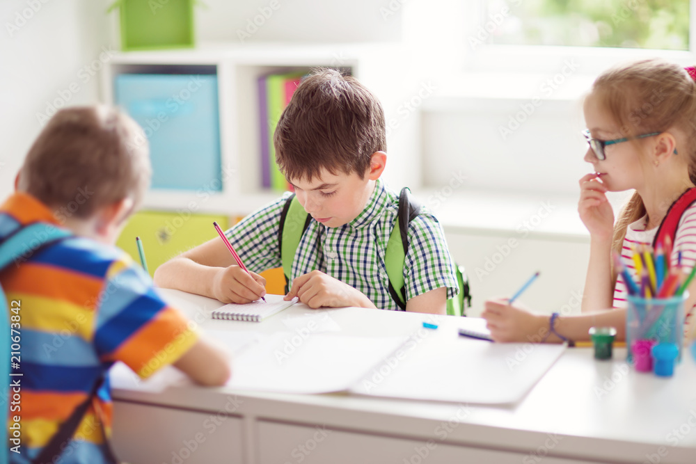 Children sitting in the room with books. Pupils writing at school Children sitting in the room with books. Pupils writing at school