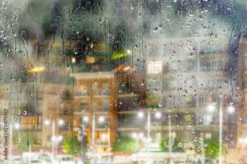Fondo abstracto de ciudad a través de la ventana.Noche lluviosa y calles de la ciudad. Gotas de lluvia en el cristal