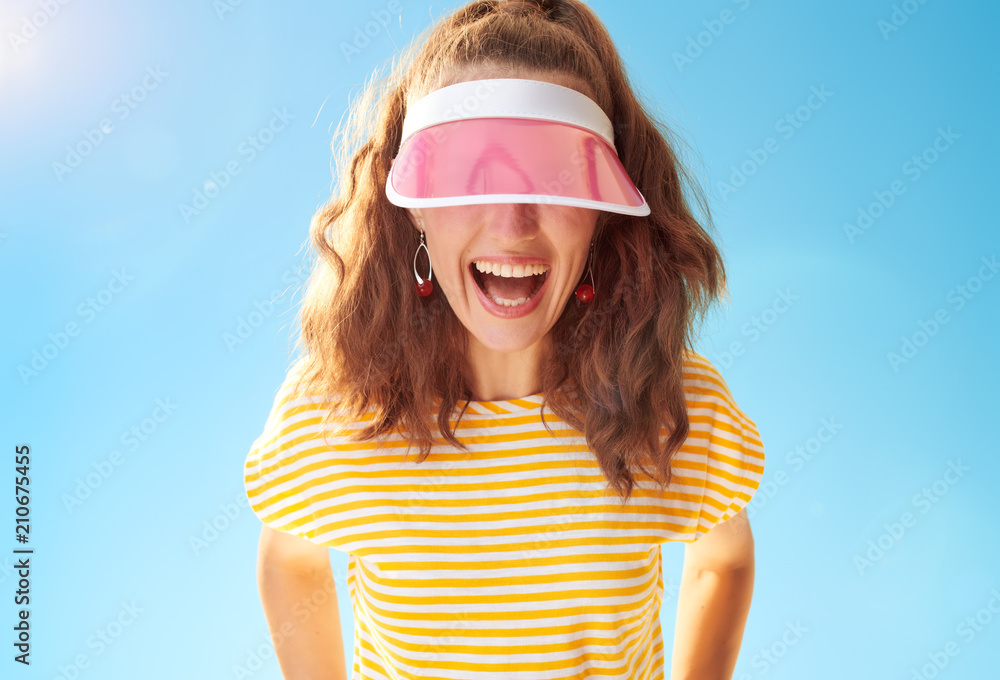 cheerful young woman against blue sky hiding behind sun visor cheerful young woman against blue sky hiding behind sun visor