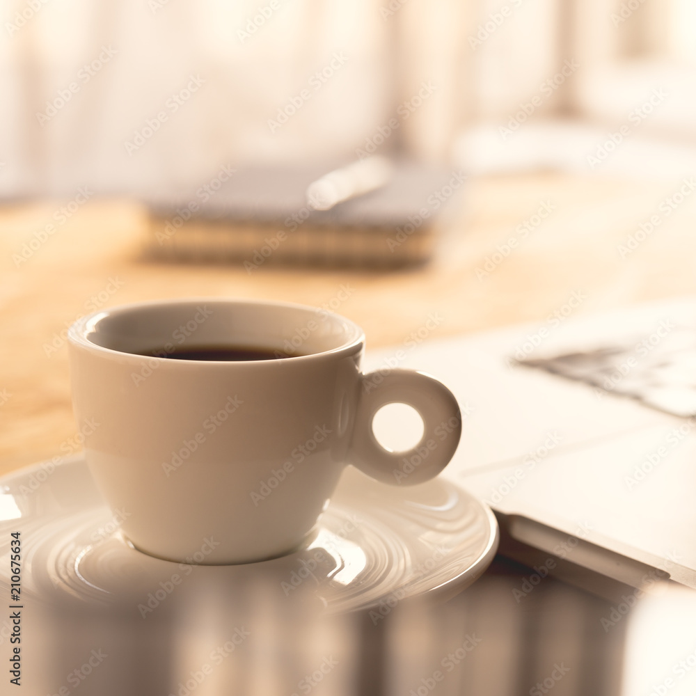 Coffee cup and laptop at office desk. Morning coffee at work. Coffee cup and laptop at office desk. Morning coffee at work.