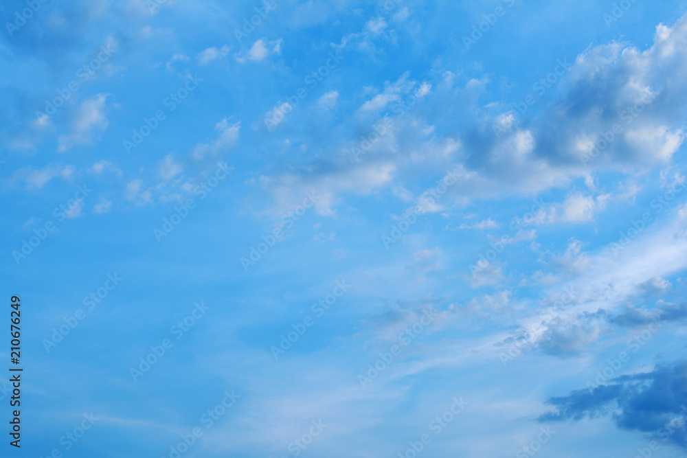 Evening blue sky with clouds at sunset. Clouds are illuminated by the rays of the setting sun.