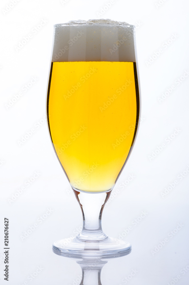 Beer glass with light cold beer with bubble froth on light backg Beer glass with light cold beer with bubble froth on light backg