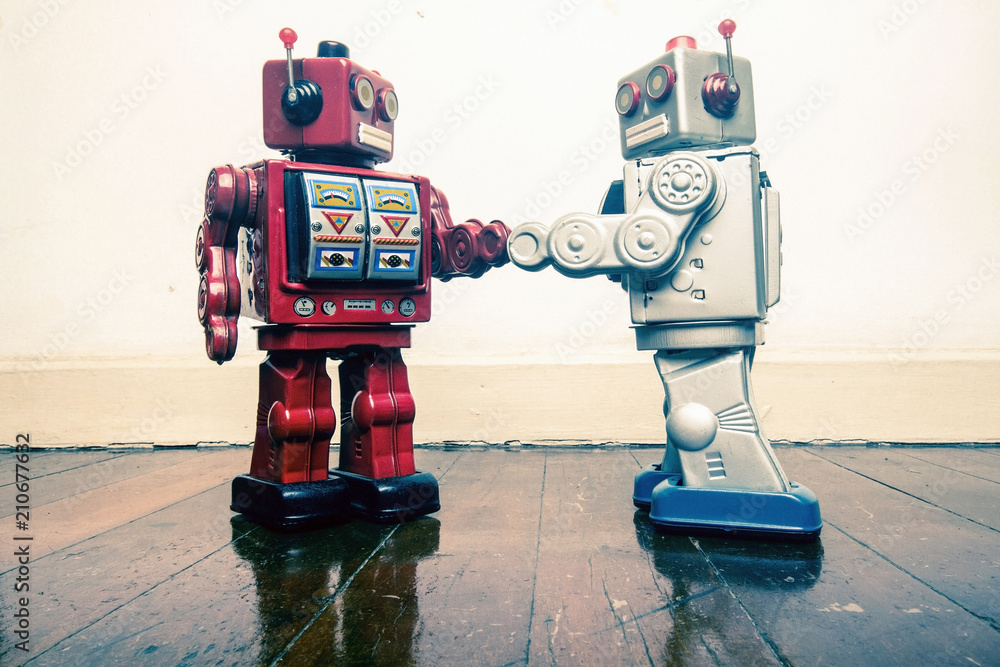 two vintage robot shake hands on a old wooden floor - obrazy, fototapety, plakaty 