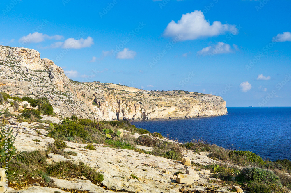 Felsige Strandlandschaft auf Malta in der Nähe der Blauen Grotte an einem sonnigen Tag mit wenigen Wolken Felsige Strandlandschaft auf Malta in der Nähe der Blauen Grotte an einem sonnigen Tag mit wenigen Wolken