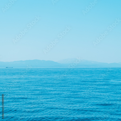 alien mountain landscape and sea. bright neon blue colors. minimal and surreal. summer vacation.