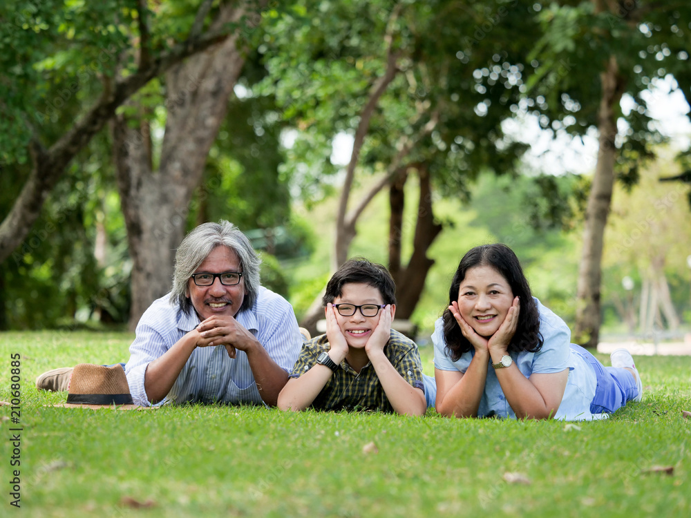 Grandparents spend the time with grandson,They are laying on grass in the garden at home. Grandparents spend the time with grandson,They are laying on grass in the garden at home.