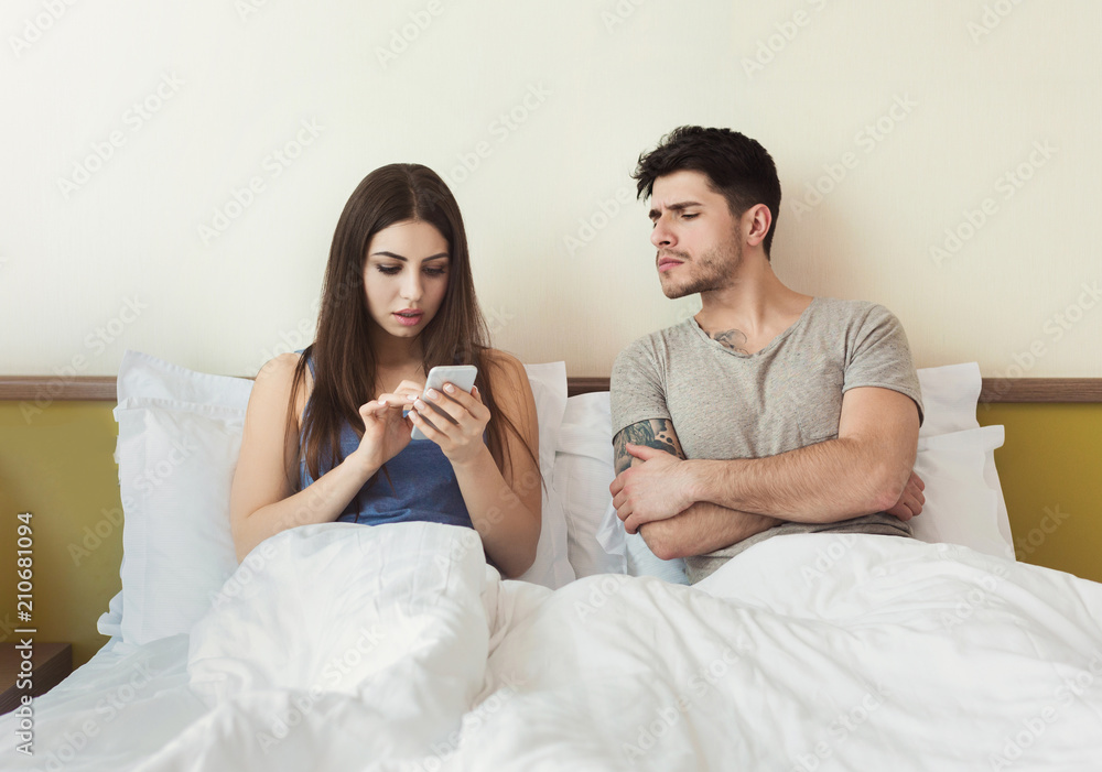 Jealous husband watching wife mobile phone on the bed Jealous husband watching wife mobile phone on the bed