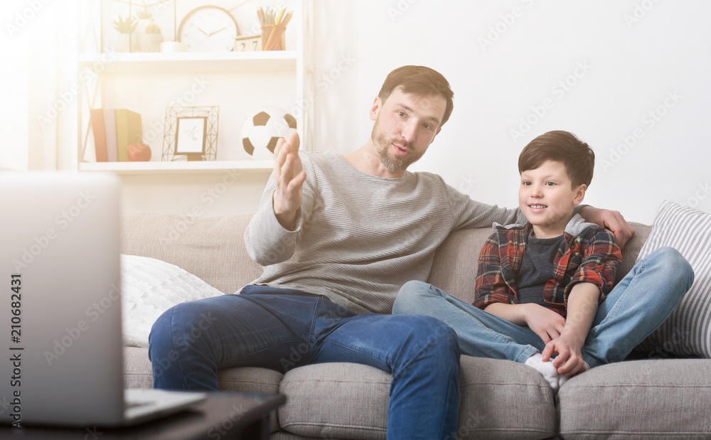 Happy father and son watching a movie on a laptop at home