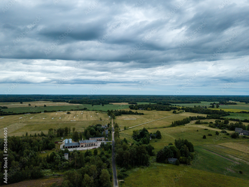 drone image. aerial view of rural area with houses and roads under heavy and dark dramatic rain clouds in summer day. night photo