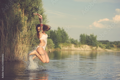 Fototapeta Naklejka Na Ścianę i Meble -  Tattooed Woman Jumping from Water