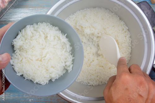 Cooked rice on plastic ladle in electric rice cooker