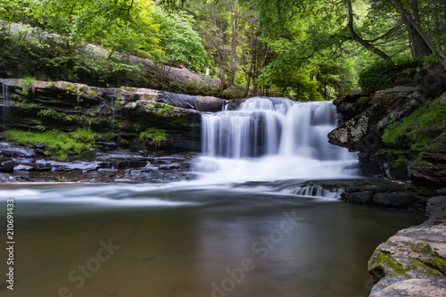 A forest waterfall with motion and wide pool in front. © DSBurnside