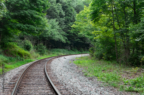 Train tracks lead into a curve or bend in the forest of West Virginia.