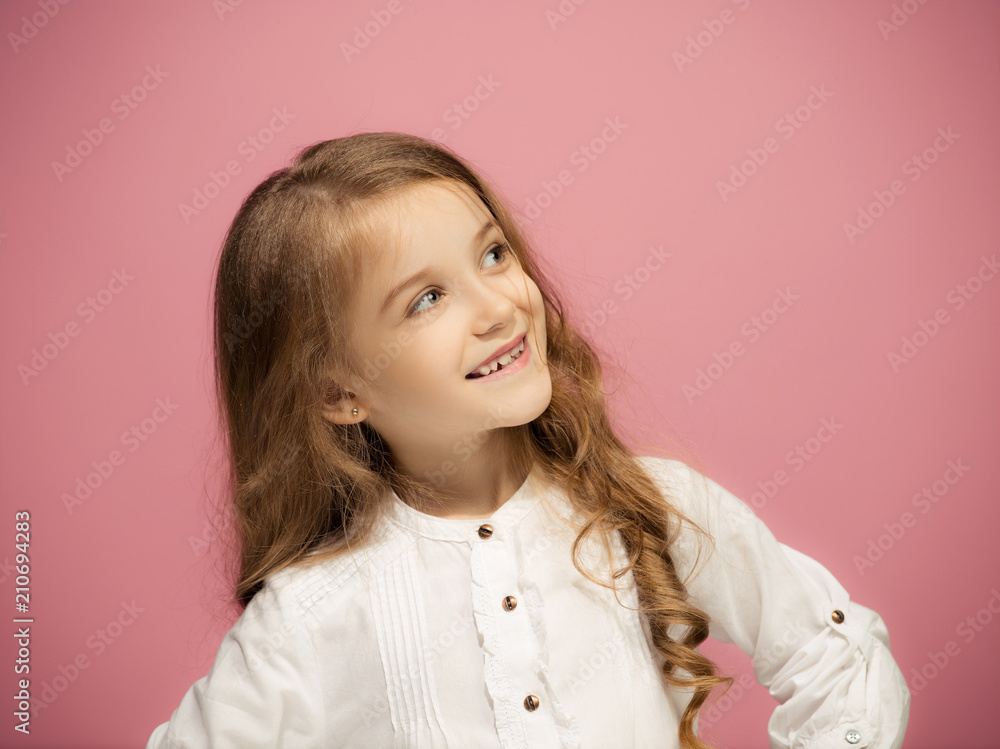 The happy teen girl standing and smiling against pink background. The happy teen girl standing and smiling against pink background.