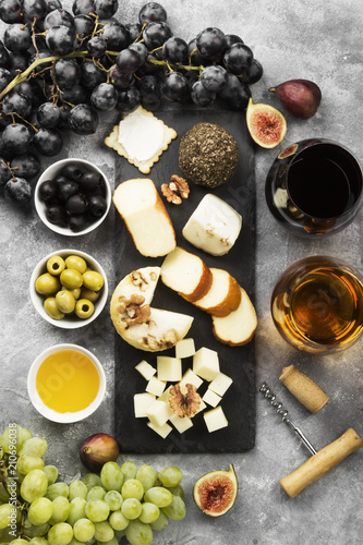 Snacks with wine - various types of cheeses, figs, nuts, honey, grapes on a gray background. Top view. Food background