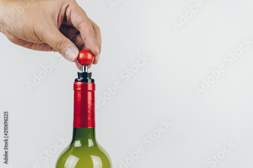 close up of hand using a wine stopper to close a red wine bottle photo