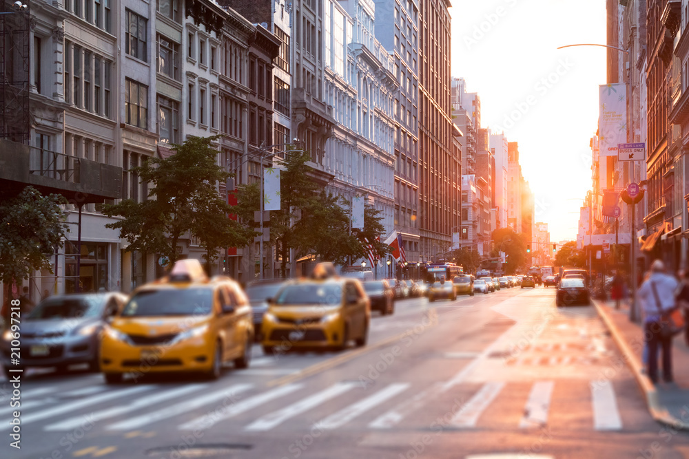 Naklejka premium Światło słoneczne świeci wzdłuż ruchliwej ulicy w Nowym Jorku z taksówkami zatrzymanymi na skrzyżowaniu