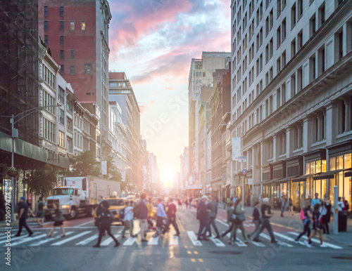 Obraz na płótnie Crowds of people crossing an intersection in Manhattan, New York City with the colorful light of sunset in the background w salonie