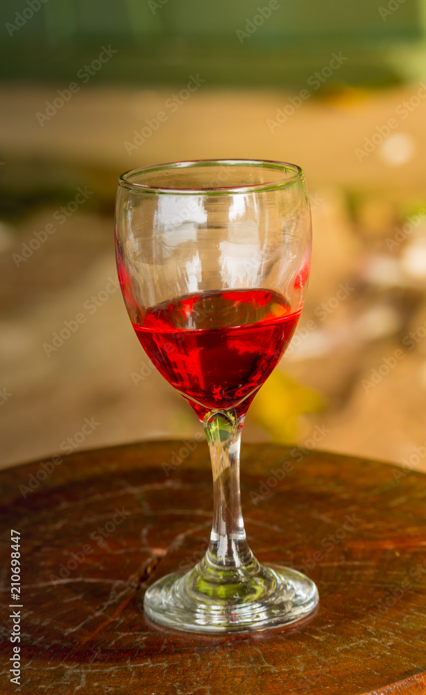 glass of red wine is placed on a wooden table. In the morning sea atmosphere of the summer.