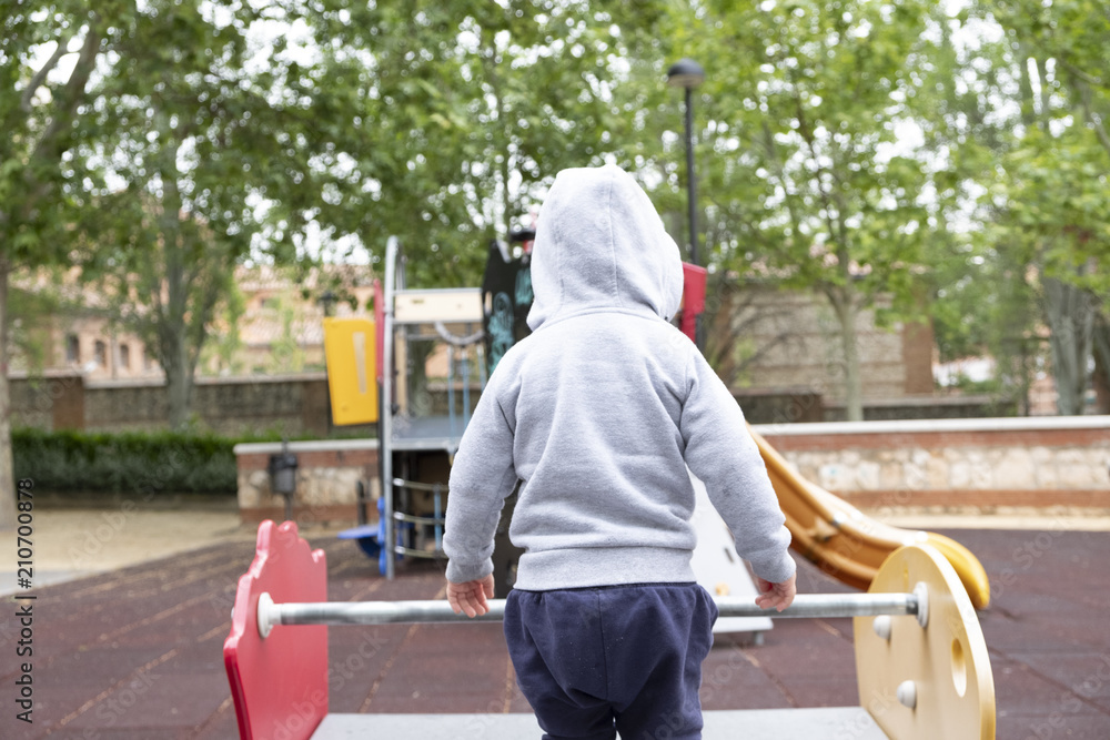 Child under two years playing in the park with a gray jacket and blue pants. Child under two years playing in the park with a gray jacket and blue pants.