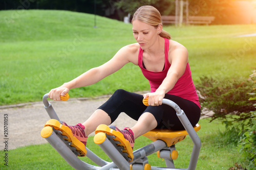 Sportliche Frau bei Fitness, Training, Sport und Workout an Trainigsgerät für Kraftsport mit Park