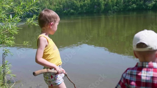 Two children catch fish with fishing rods on the river Bank. Beautiful summer landscape. Outdoor recreation. photo